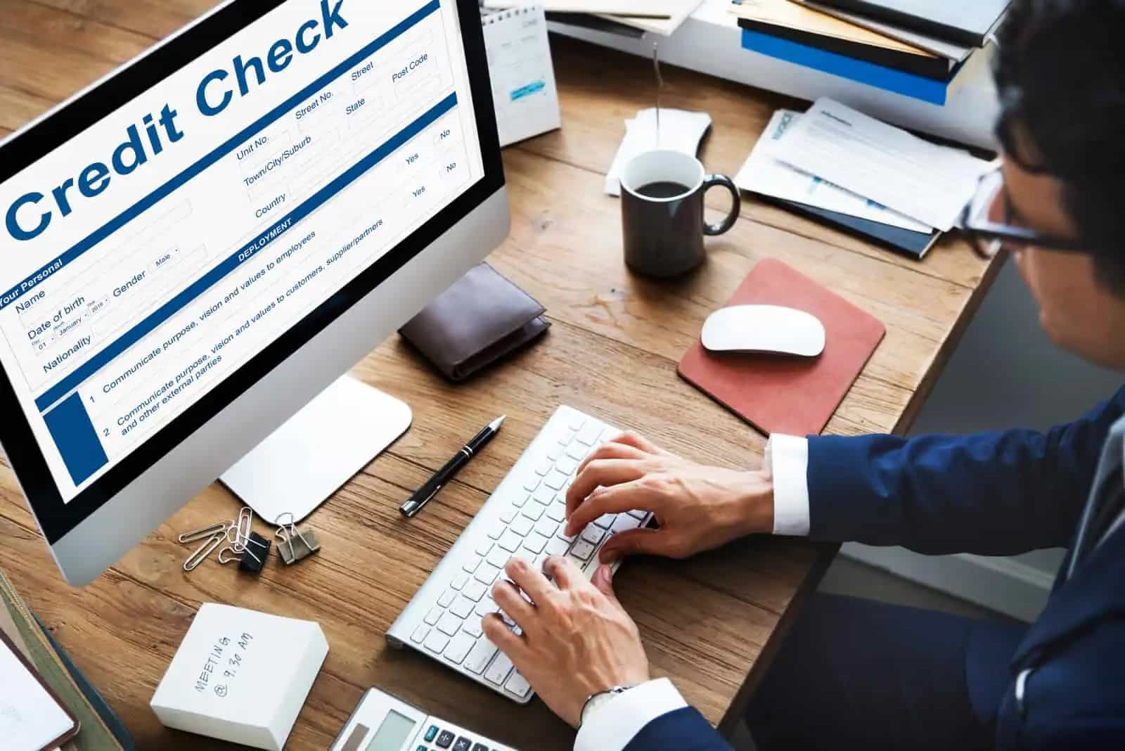 Tela de computador mostrando um formulário de verificação de crédito, com homem digitando no teclado
