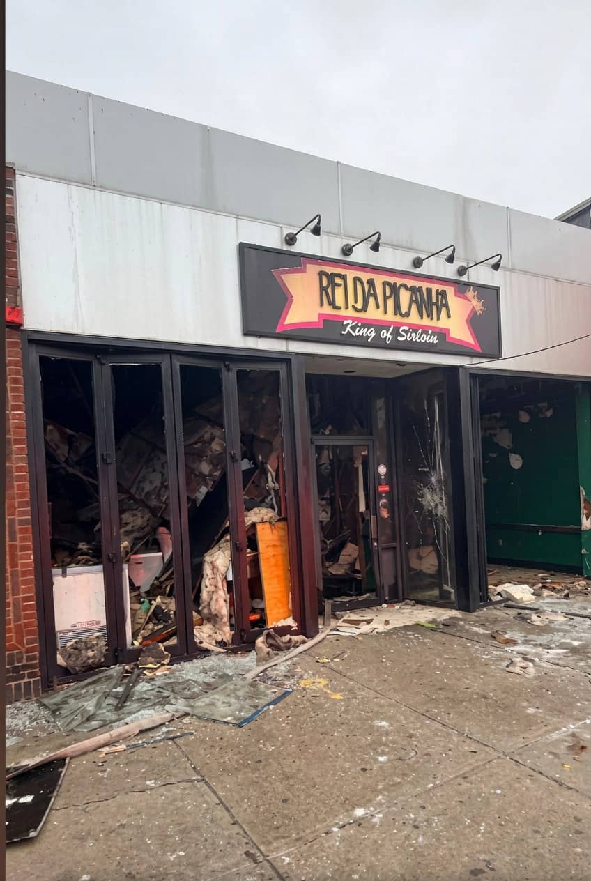 Fachada do restaurante Rei da Picanha destruída por incêndio, com vidros quebrados, entulho no chão e a placa ainda de pé