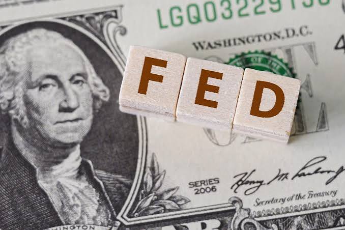 Cubos de madeira formando a palavra FED sobre uma nota de dólar