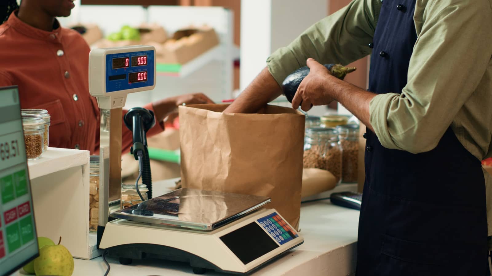 Funcionário de mercearia pesando e embalando produto para cliente