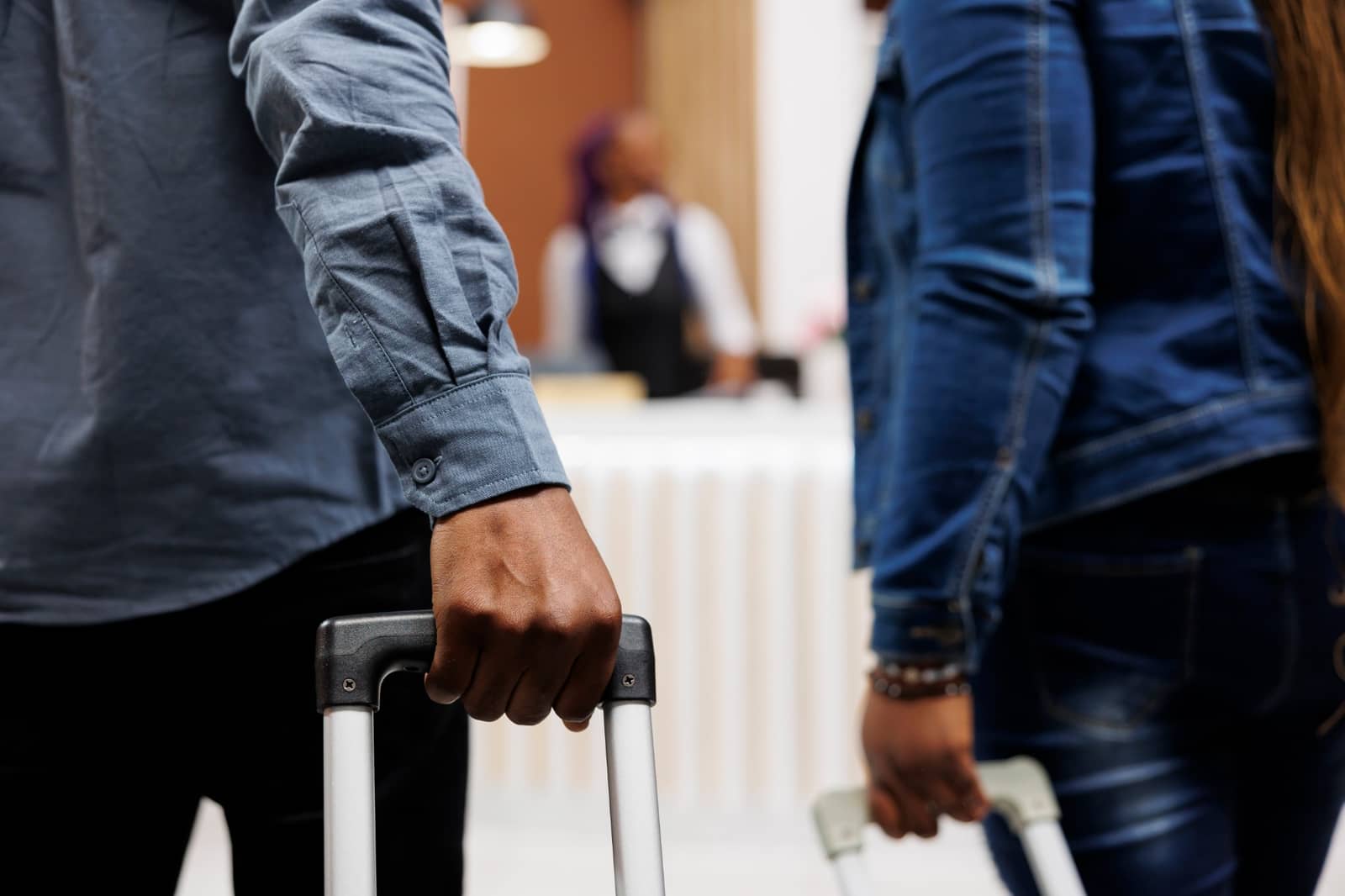 Duas pessoas puxando malas de viagem em corredor de hotel ou aeroporto